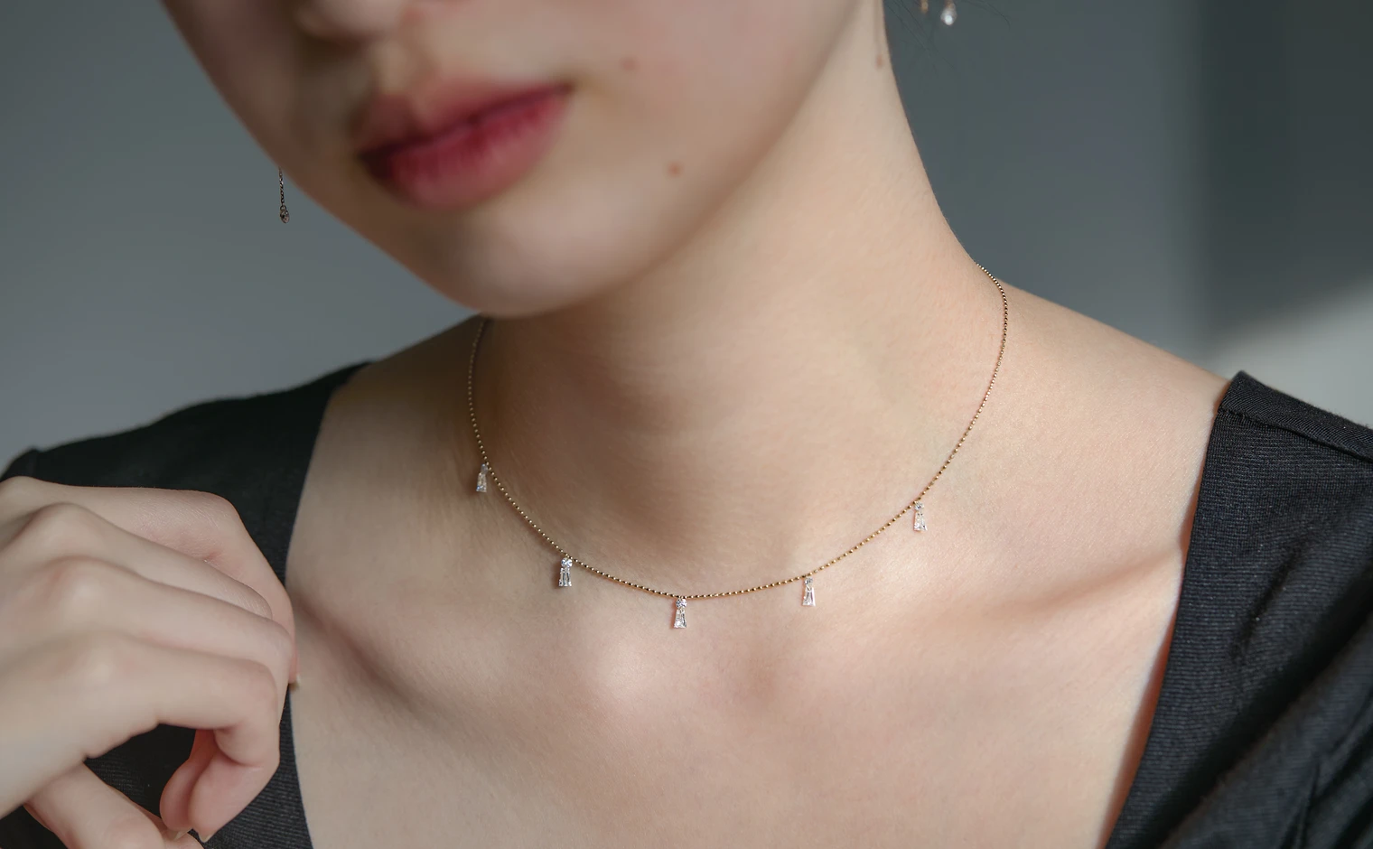 A kataoka Less is More necklace with baguette diamonds worn against a dark top, showing the precision of each diamond's placement along the chain